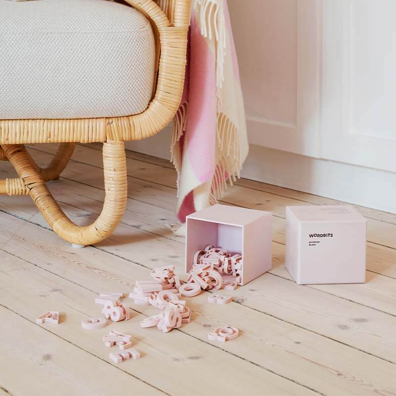 Blush Wordbits magnet letters packaging box oppen on a Scandinavian wood floor with letters spilling out