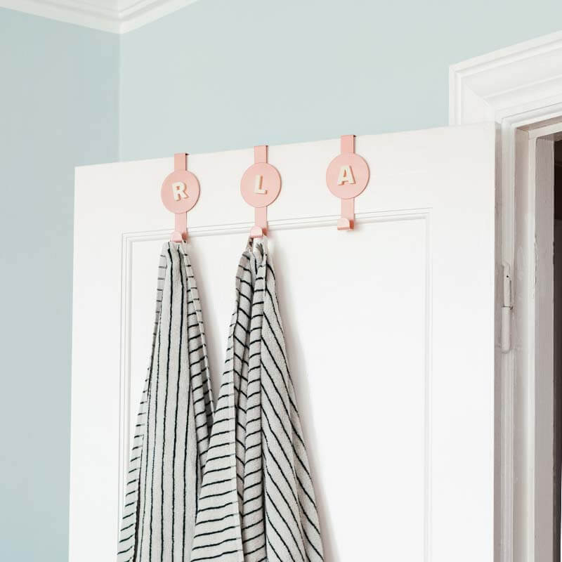 pink metal hooks with bone white magnet letters from wordbits showing the first initial of each towel's owner. Danish apartment light blue walls with white ceiling and door